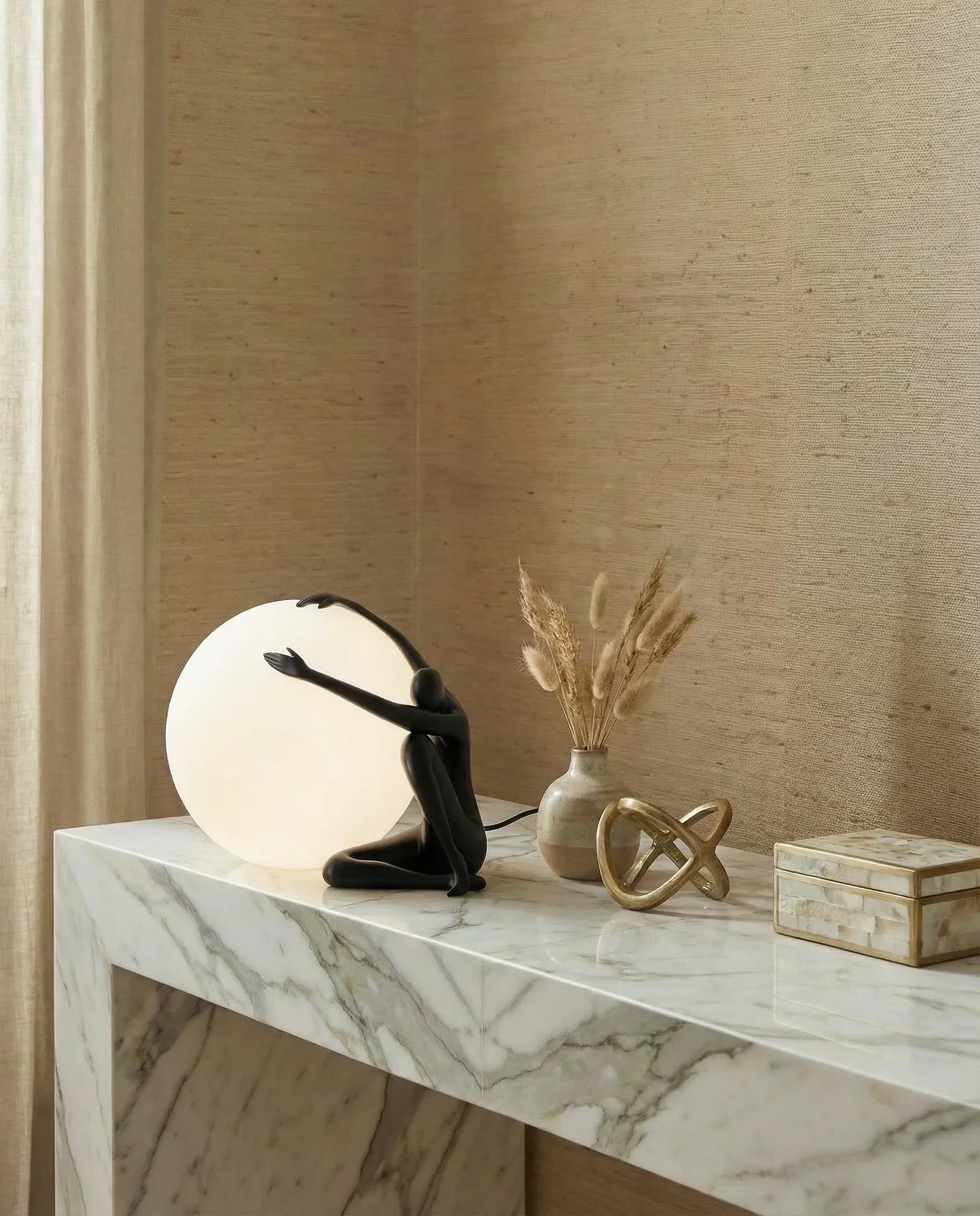 Human figurine table lamp holding a glowing sphere