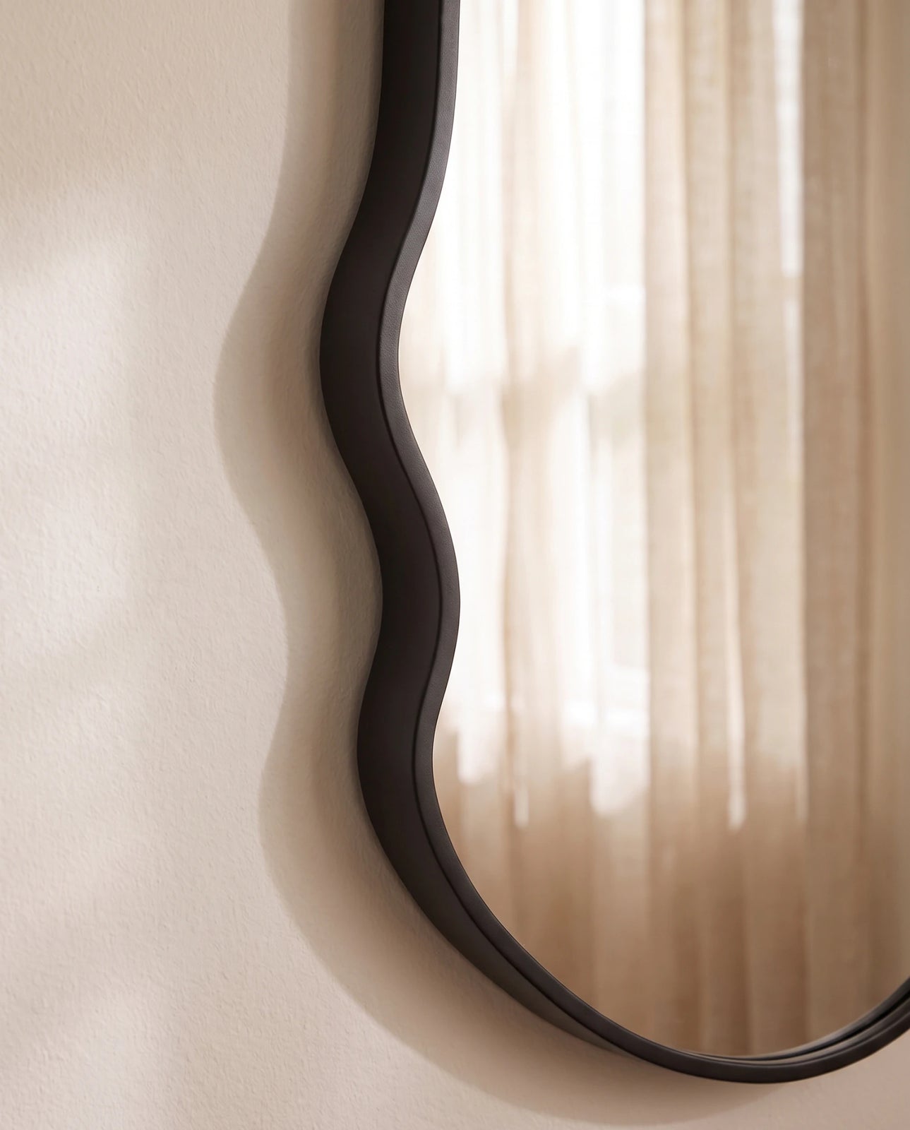 Onda black irregular wall mirror in a Dubai living room
